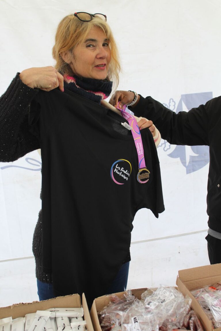 Bénévole présentant le t-shirt et la médaille